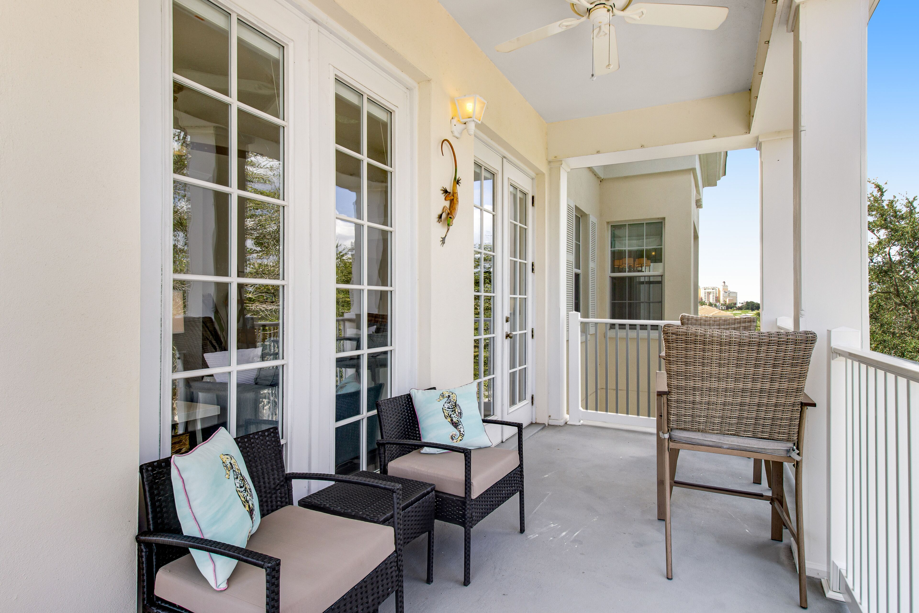A covered porch with wicker furniture, large windows, and a ceiling fan.