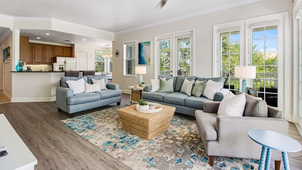 A spacious living room with a large sofa, a coffee table, and a dining area with a kitchen in the background. - Spacious and Inviting Getaway Condo Close to Disney and Universal (Kissimmee)