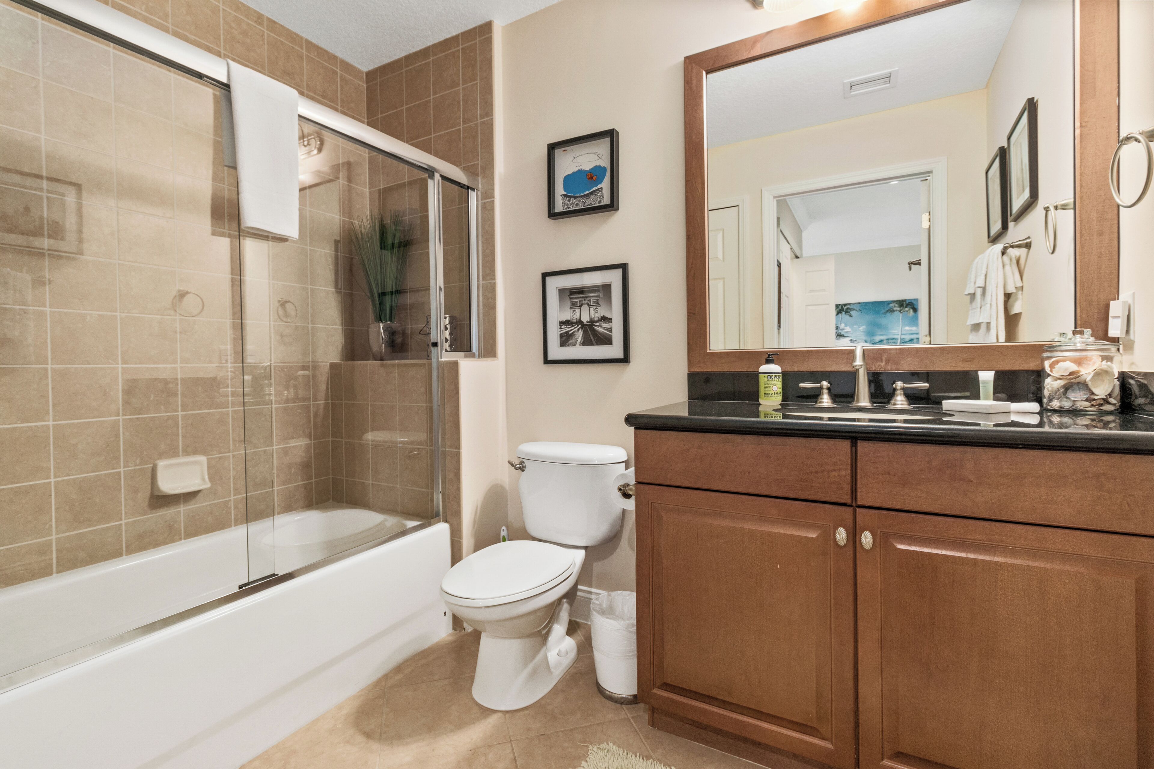 A bathroom with a bathtub, toilet, and wooden vanity.