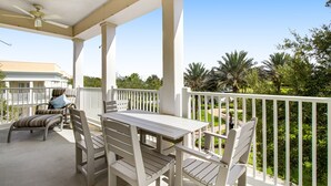 A covered outdoor area with a table and chairs, a ceiling fan, and a view of greenery and a building in the background. - Spacious and Inviting Getaway Condo Close to Disney and Universal (Kissimmee)