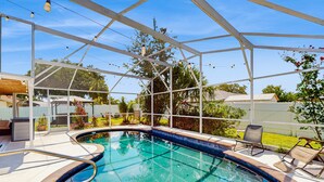 Una piscina con zona coperta, sedie a sdraio e vista sul giardino circostante.