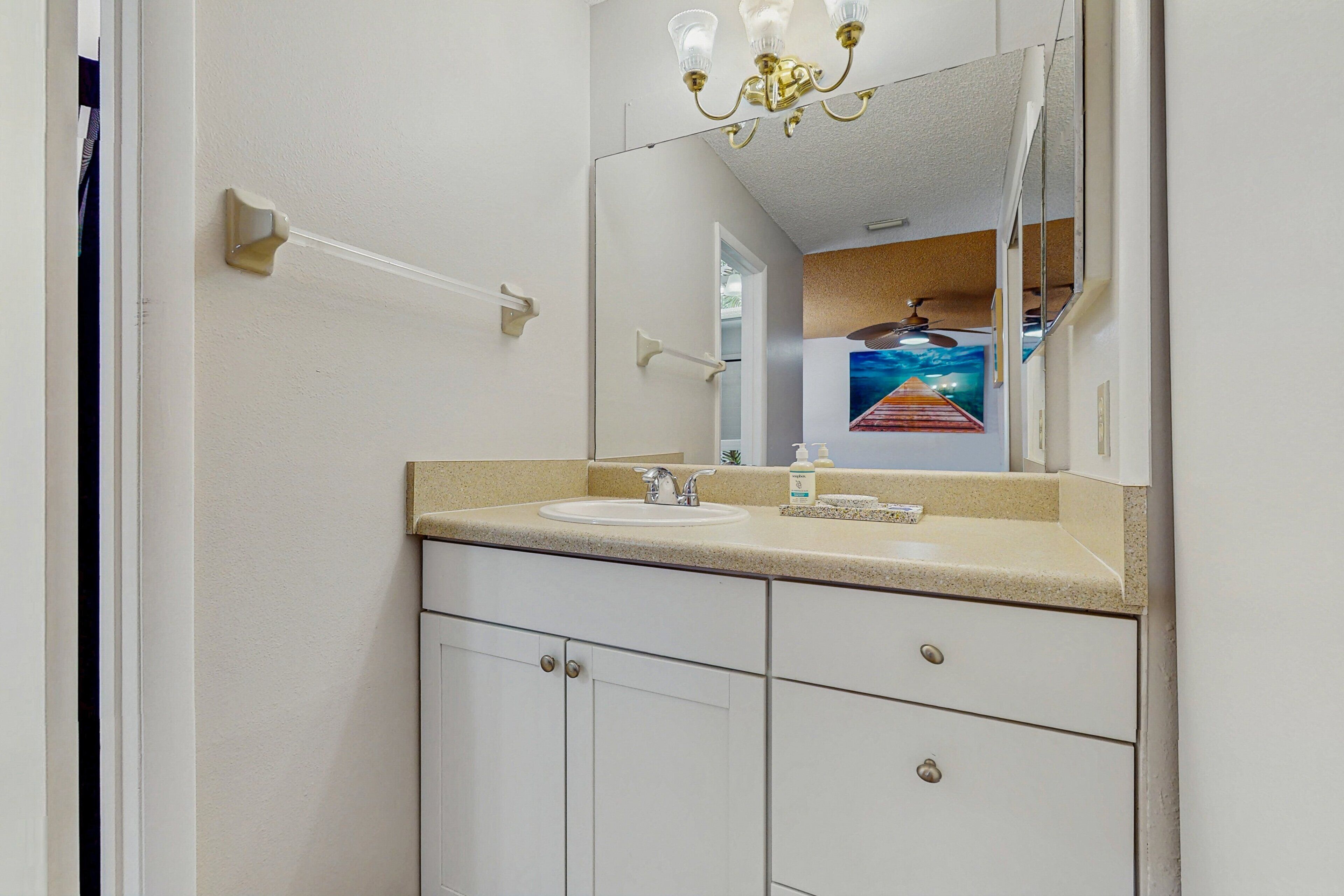 A bathroom with a white sink, a mirror, and a chandelier.