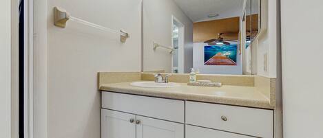 A bathroom with a white sink, a mirror, and a chandelier.