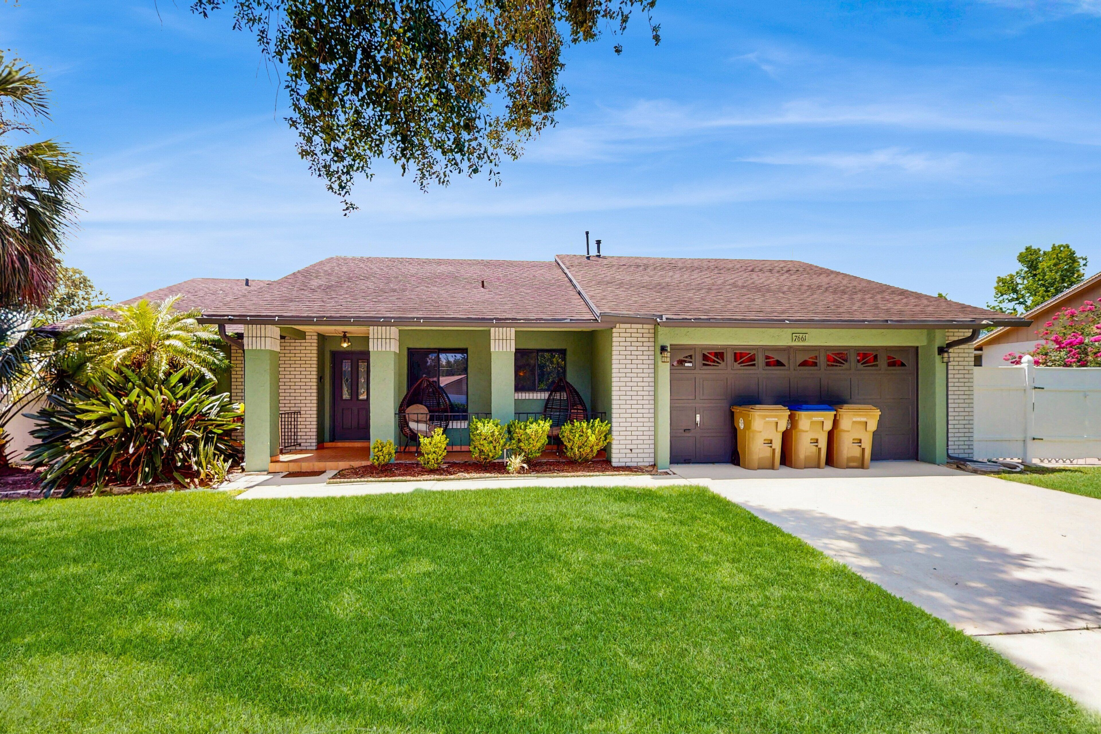 A single-story house with a garage, a well-maintained lawn, and a clear sky.