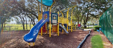 A playground with a slide, climbing structures, and a fenced area.