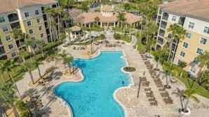 A resort with a large swimming pool, multiple buildings, and palm trees. - Comfy Condo With Central AC, Wifi, Private Washer/dryer Minutes to Theme Parks (Orlando)