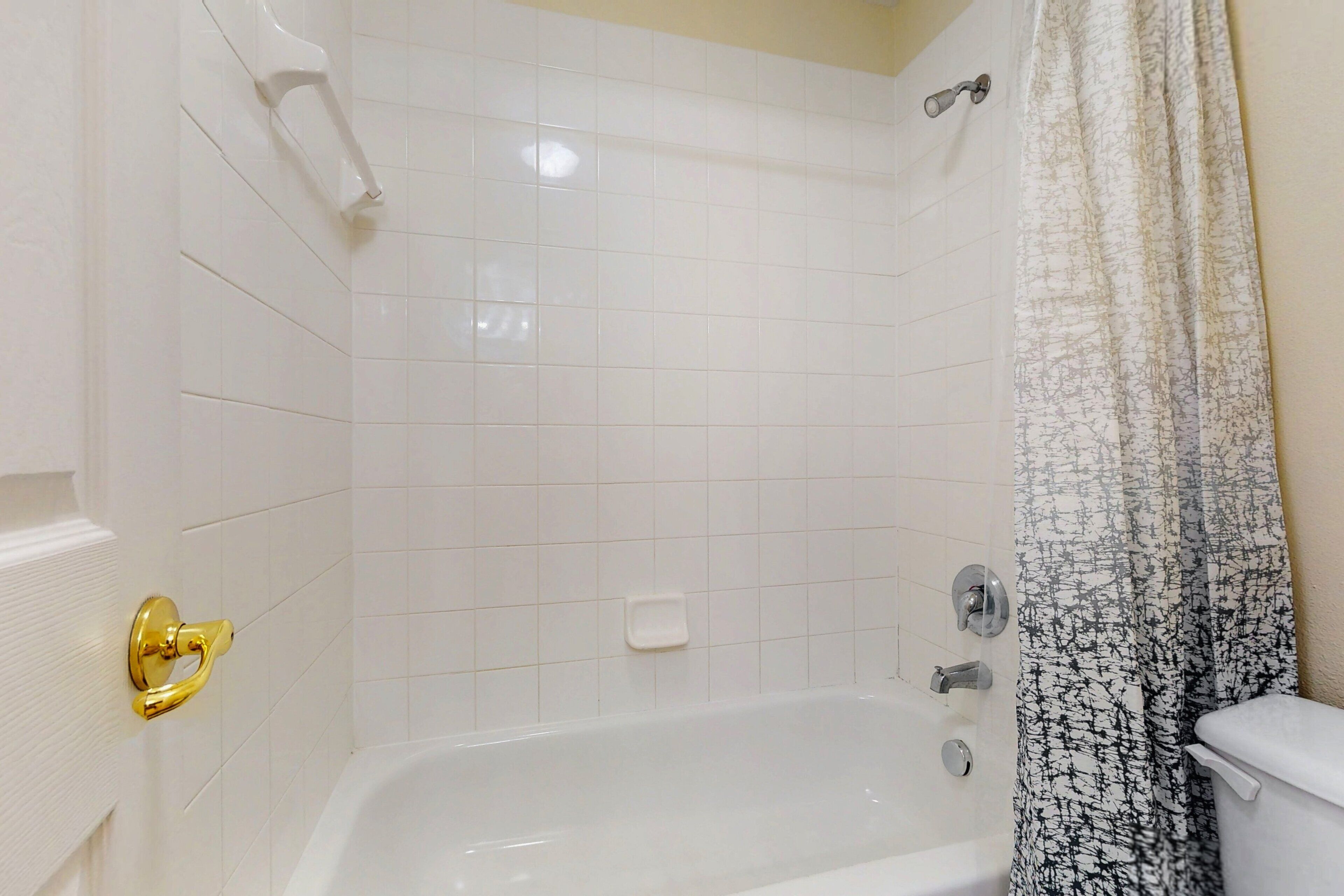Une salle de bain avec une baignoire, des toilettes et un rideau de douche.