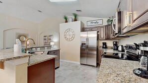 Una cocina moderna con encimeras de granito, electrodomésticos de acero inoxidable y una isla central.