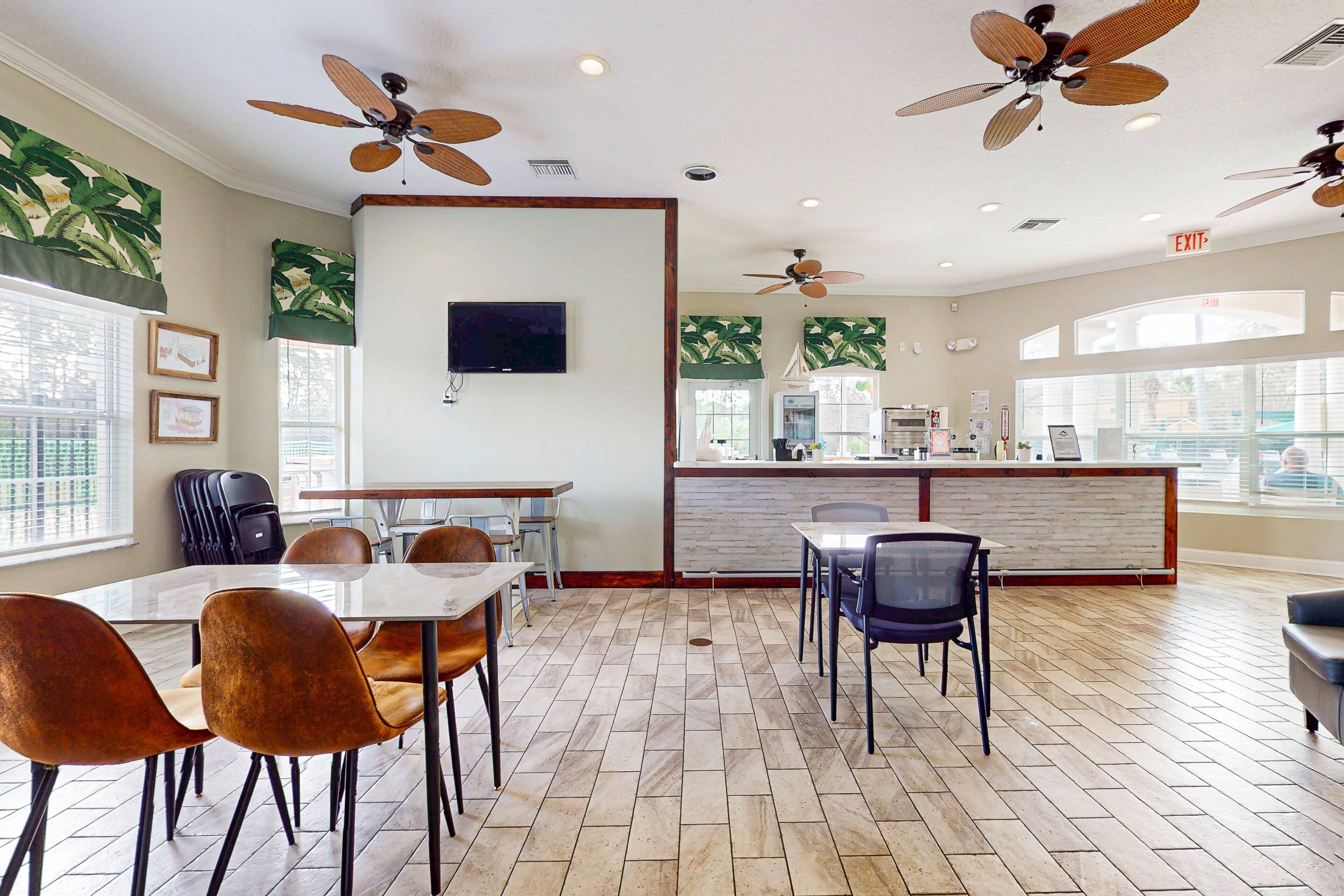 A modern dining area with wooden flooring, a central counter, and ceiling fans.