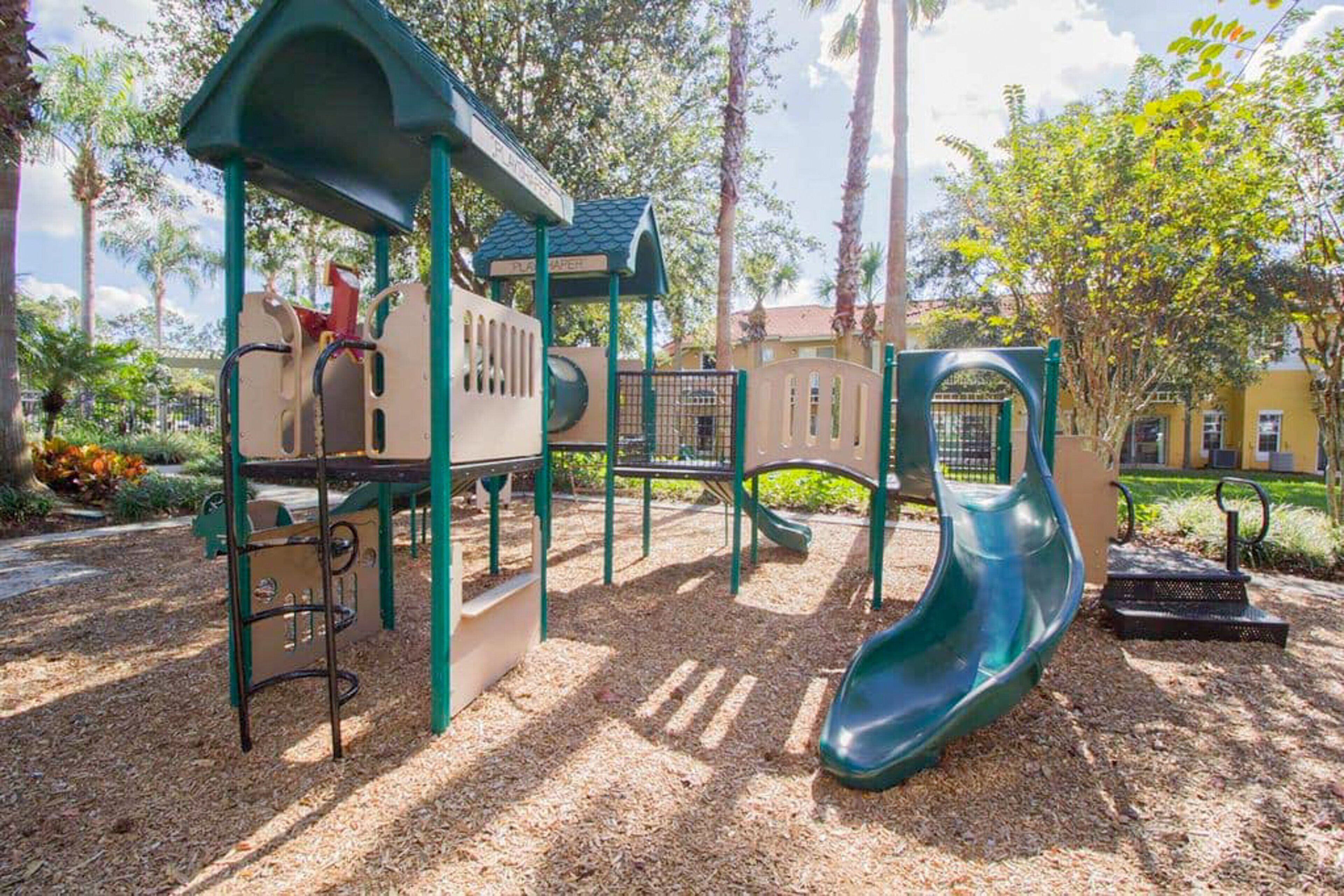 Un parc infantil amb tobogan, elements per escalar i una zona de jocs coberta.