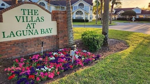 Señalización de 'The Villas at Laguna Bay', con un muro de ladrillo y un colorido macizo de flores.