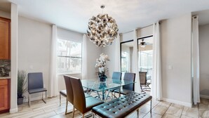 Een moderne eethoek met een glazen tafel, lederen stoelen en een gestofte bank.