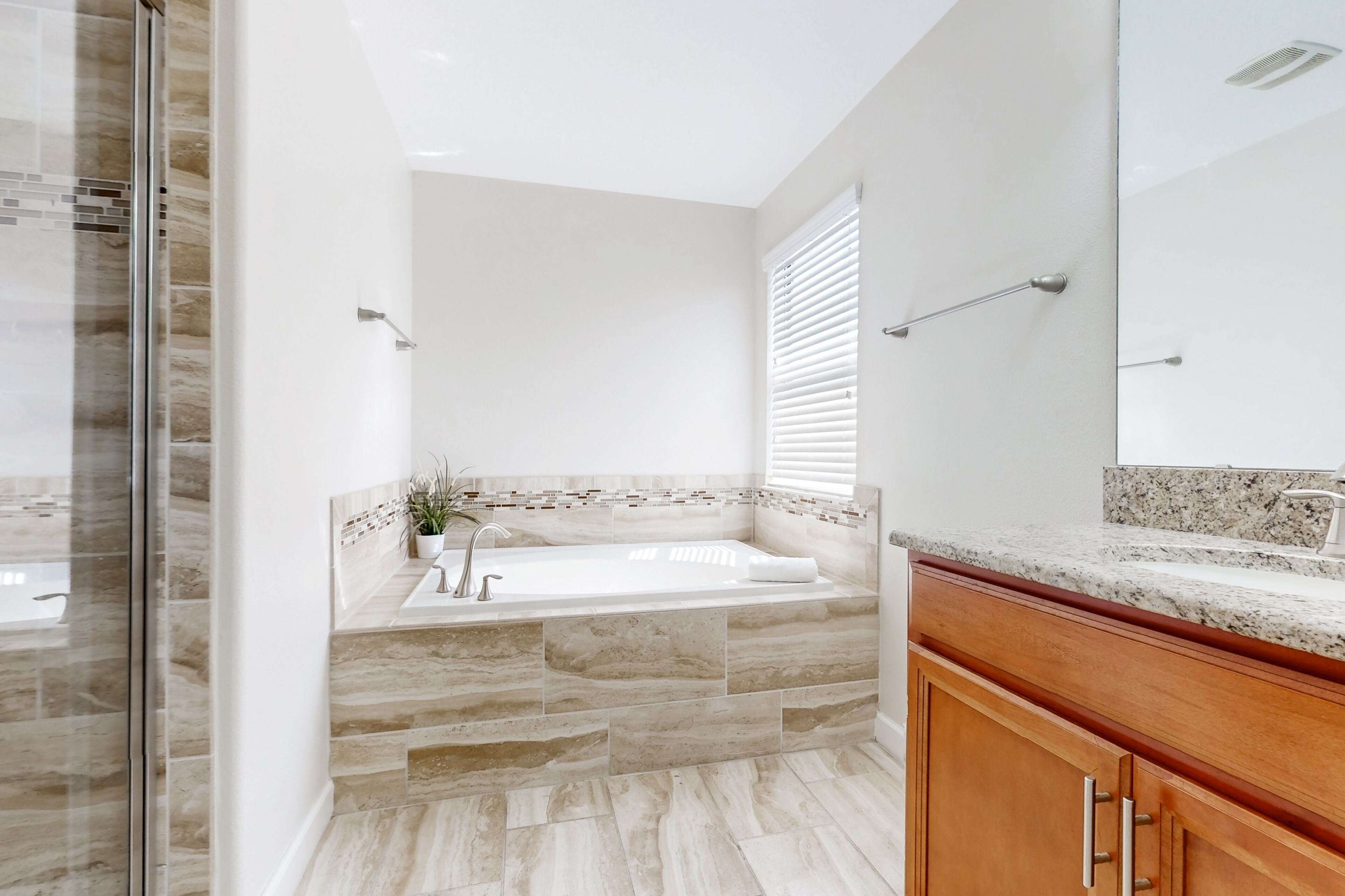 Ein modernes Badezimmer mit einer großen Badewanne, Steinfliesen und Holzschränken.
