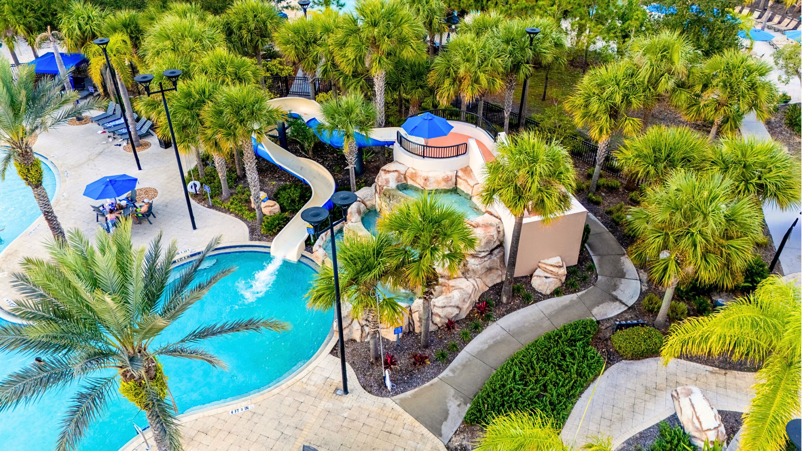 A resort with a swimming pool, palm trees, and a water slide.