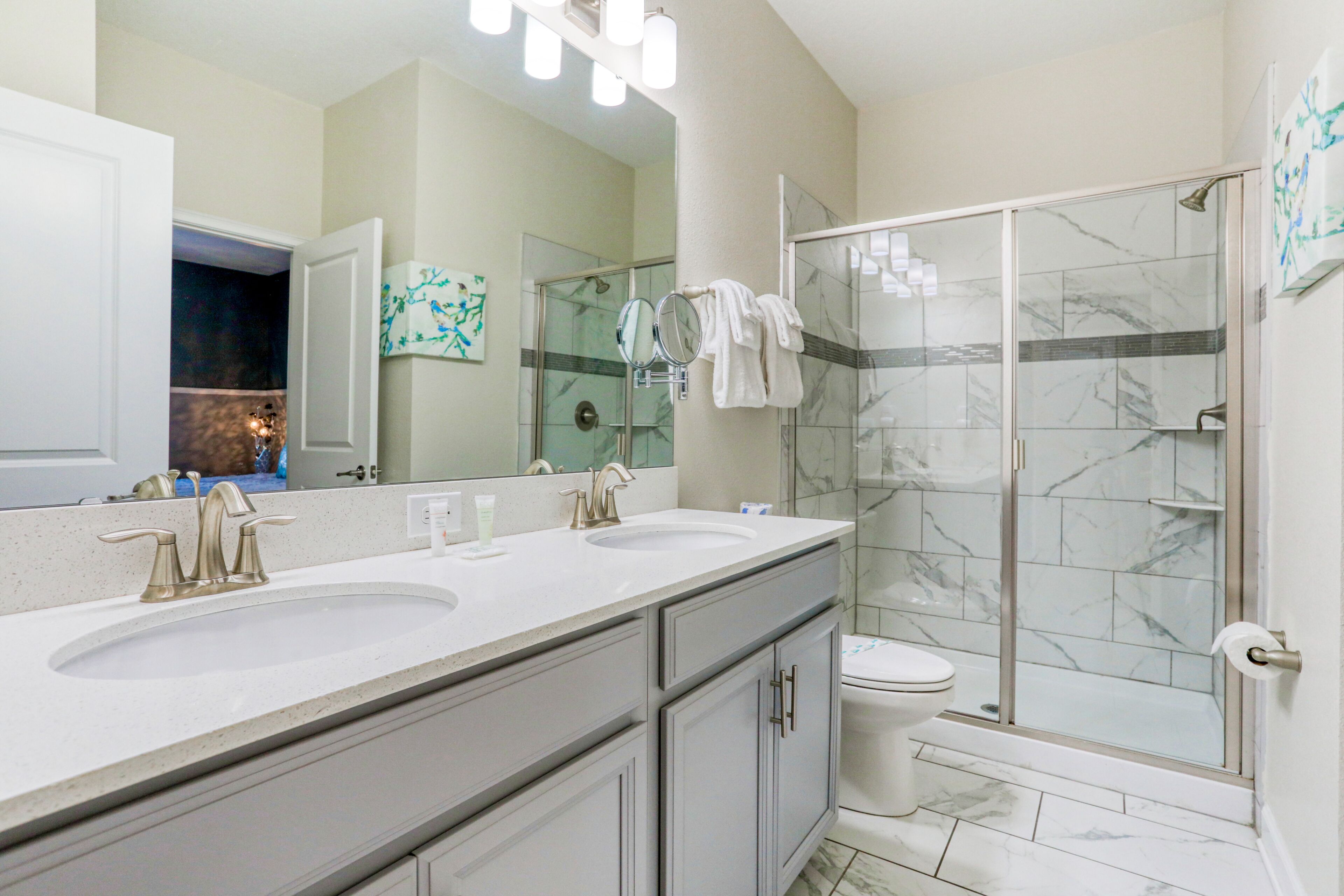 A modern bathroom with two sinks, a toilet, and a glass-enclosed shower.