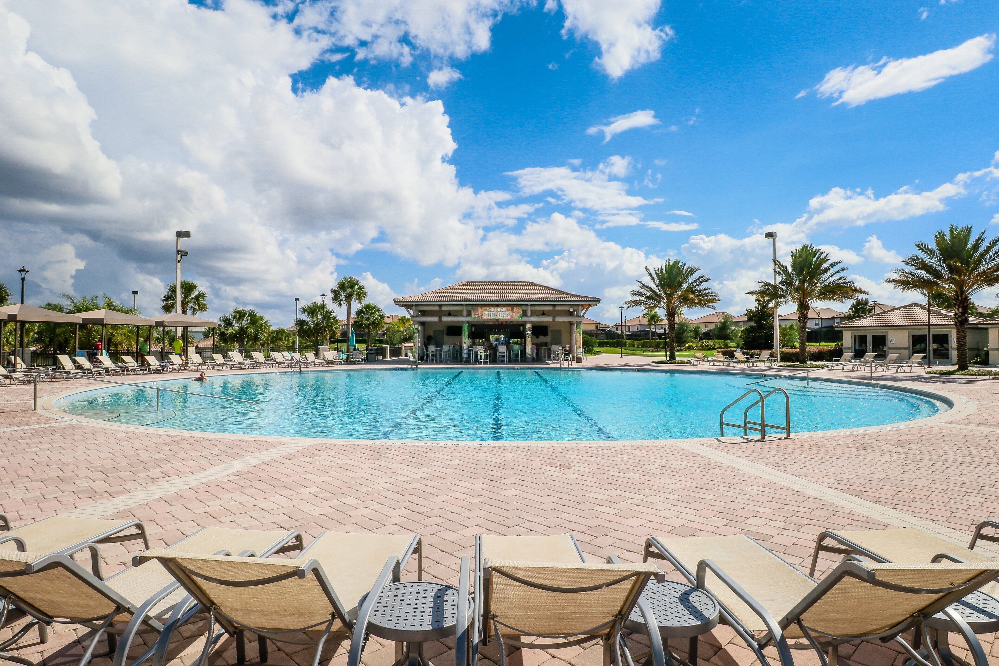 A swimming pool with lounge chairs and a covered area.