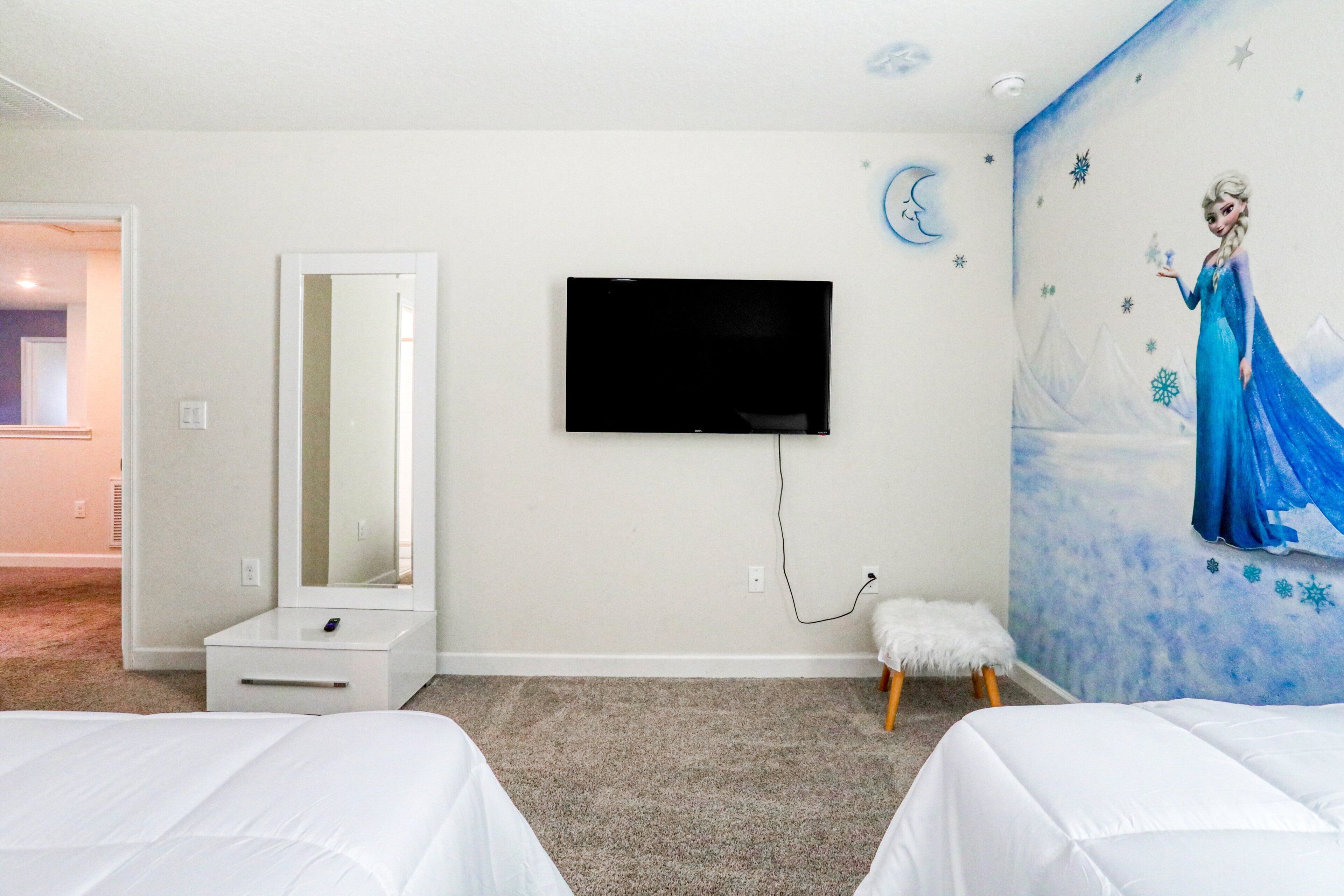A hotel room with two beds, a TV, a mirror, and a wall mural.