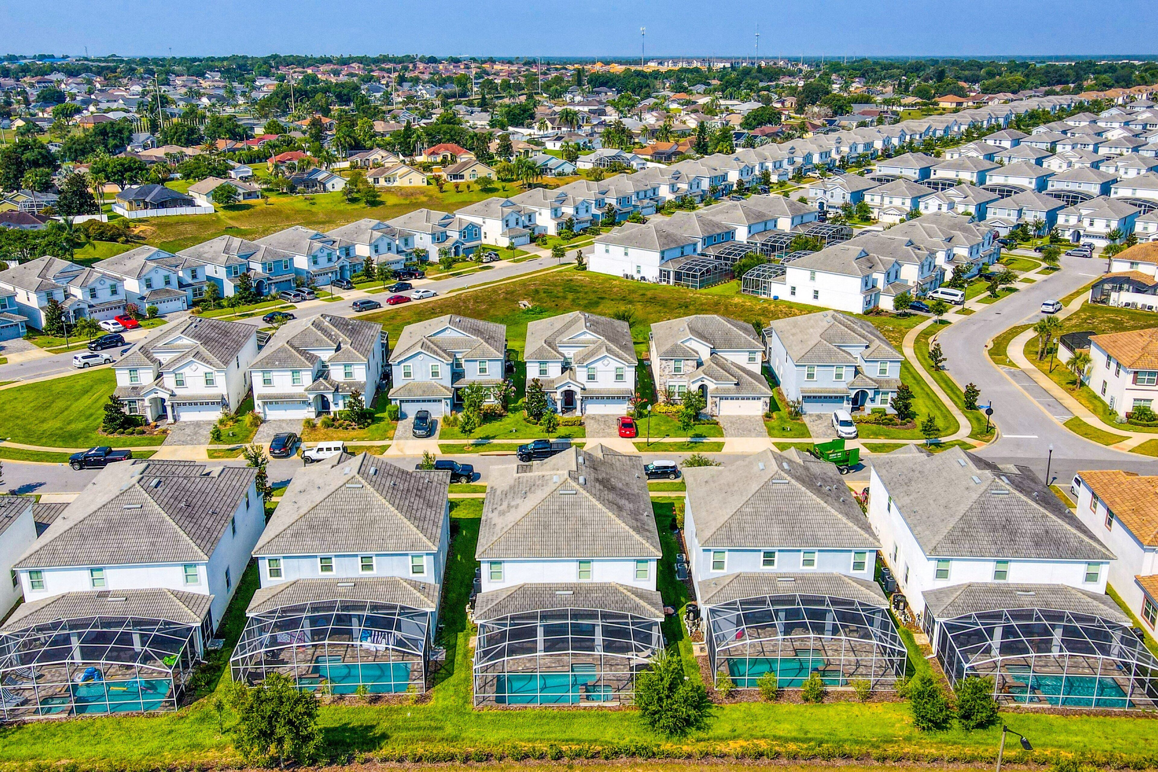 A residential area with houses, swimming pools, and a clear sky.