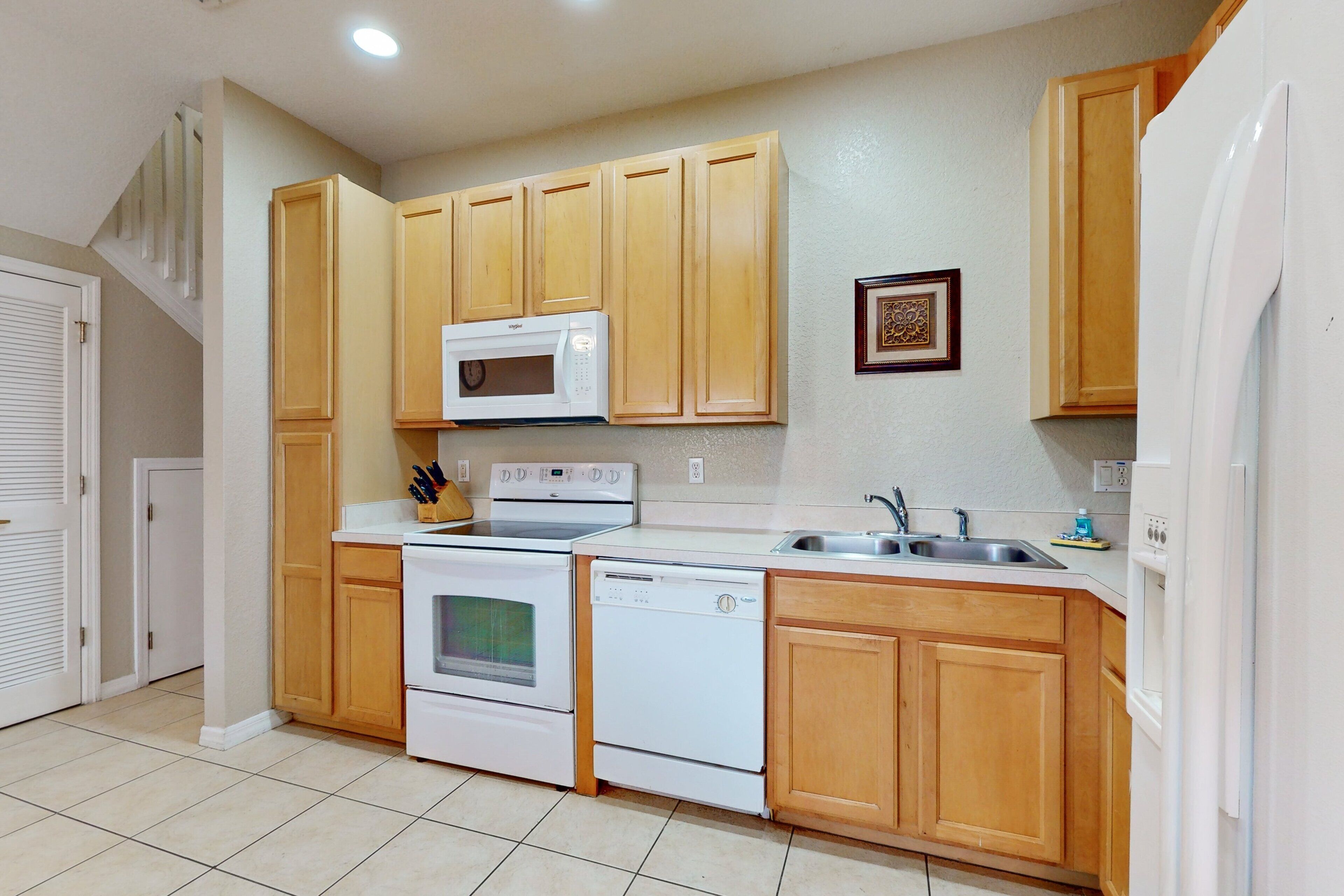 A kitchen with wooden cabinets, a microwave, an oven, a dishwasher, and a sink.
