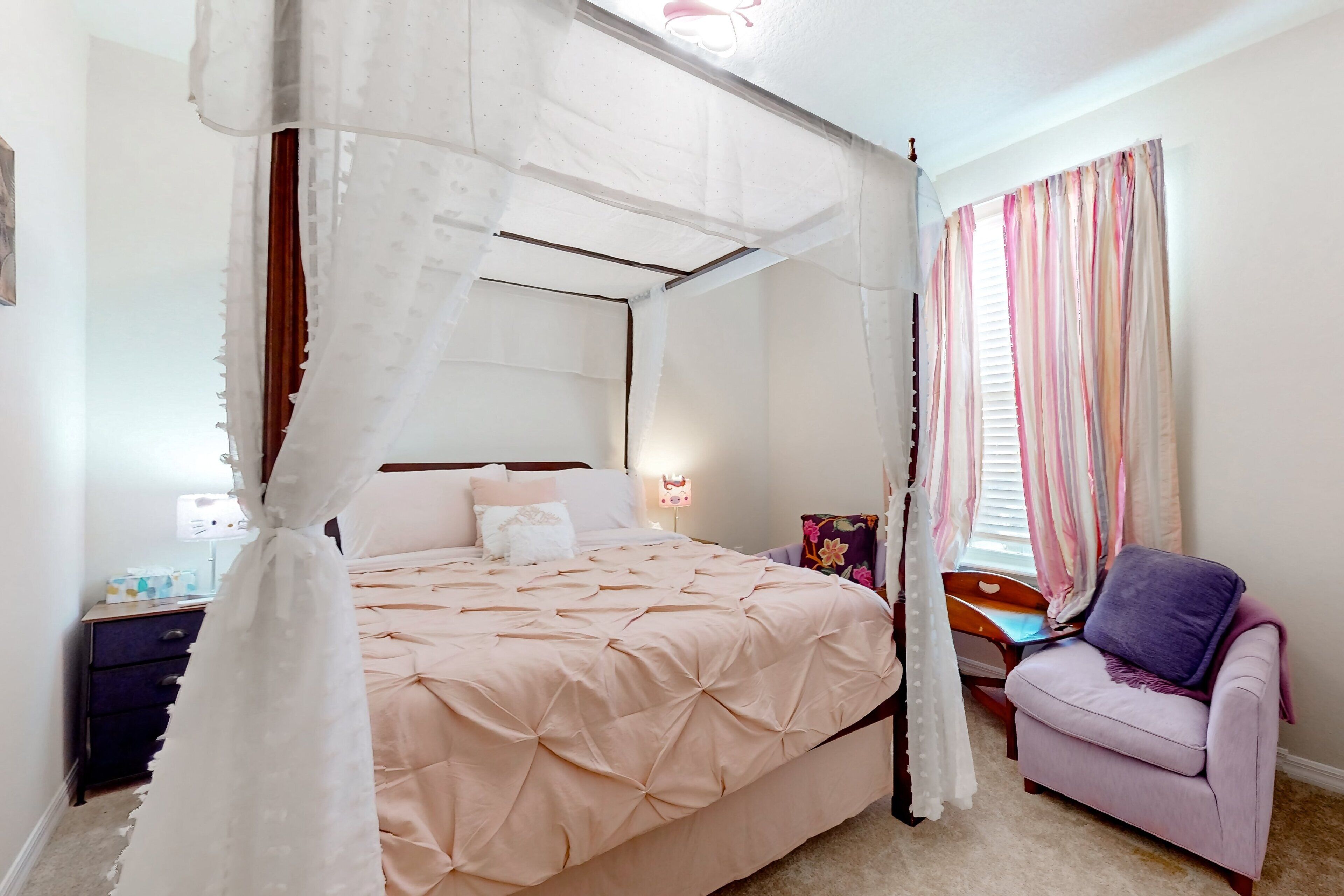 Une chambre à coucher avec un lit à baldaquin, une table de chevet, une chaise et une fenêtre avec des rideaux.