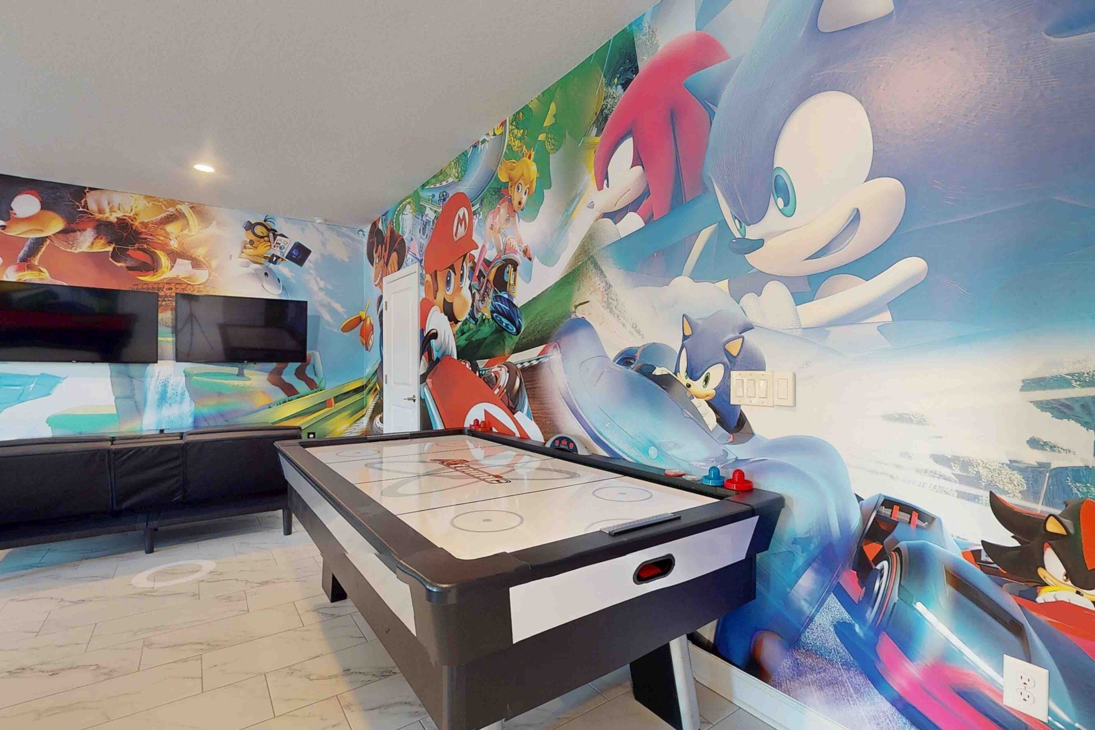 Une table de billard ornée d’une fresque murale sur le thème de Mario, un canapé et un téléviseur.