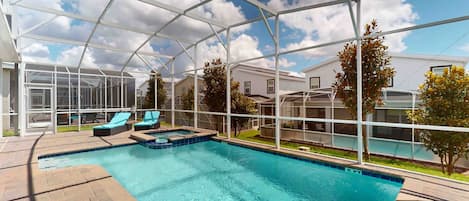 Una piscina cubierta con sillas de descanso, cielo despejado y edificios residenciales al fondo.