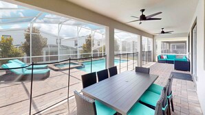 Un patio couvert avec une piscine, des sièges d’extérieur et des ventilateurs de plafond.