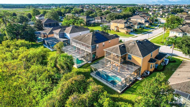 A residential area with houses, a swimming pool, and a large glass-enclosed structure. - Gorgeous Home Near Disney With Private Pool, Pool Spa, On-site Gym, Tennis, AC (Davenport)