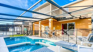A swimming pool with lounge chairs, a covered patio, and a view of the surrounding area. - Gorgeous Home Near Disney With Private Pool, Pool Spa, On-site Gym, Tennis, AC (Davenport)