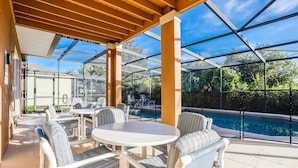 An outdoor patio with a pool, covered seating, and a view of the pool. - Gorgeous Home Near Disney With Private Pool, Pool Spa, On-site Gym, Tennis, AC (Davenport)