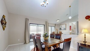 Uma sala de jantar com uma mesa de madeira, seis cadeiras e um candelabro.