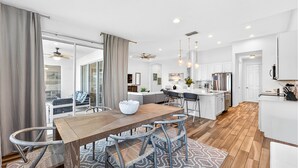 A modern kitchen with a central island, a dining area with a wooden table and metal chairs, and a living area with a sofa and a coffee table. - Spacious, Lakefront Home With a Lanai, Private Pool, Spa, & Washer/dryer (Davenport)