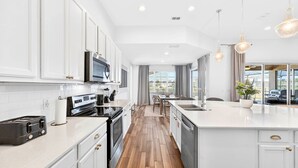 A modern kitchen with white cabinetry, a built-in oven, a microwave, and a large island with a sink. - Spacious, Lakefront Home With a Lanai, Private Pool, Spa, & Washer/dryer (Davenport)