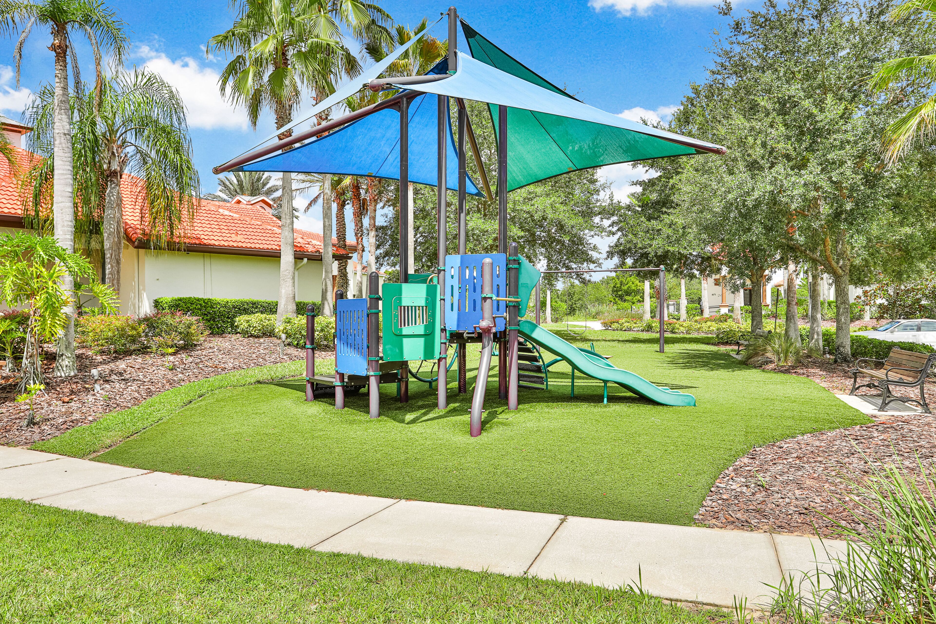 Un parque infantil con tobogán, estructuras para escalar y una zona con sombra.