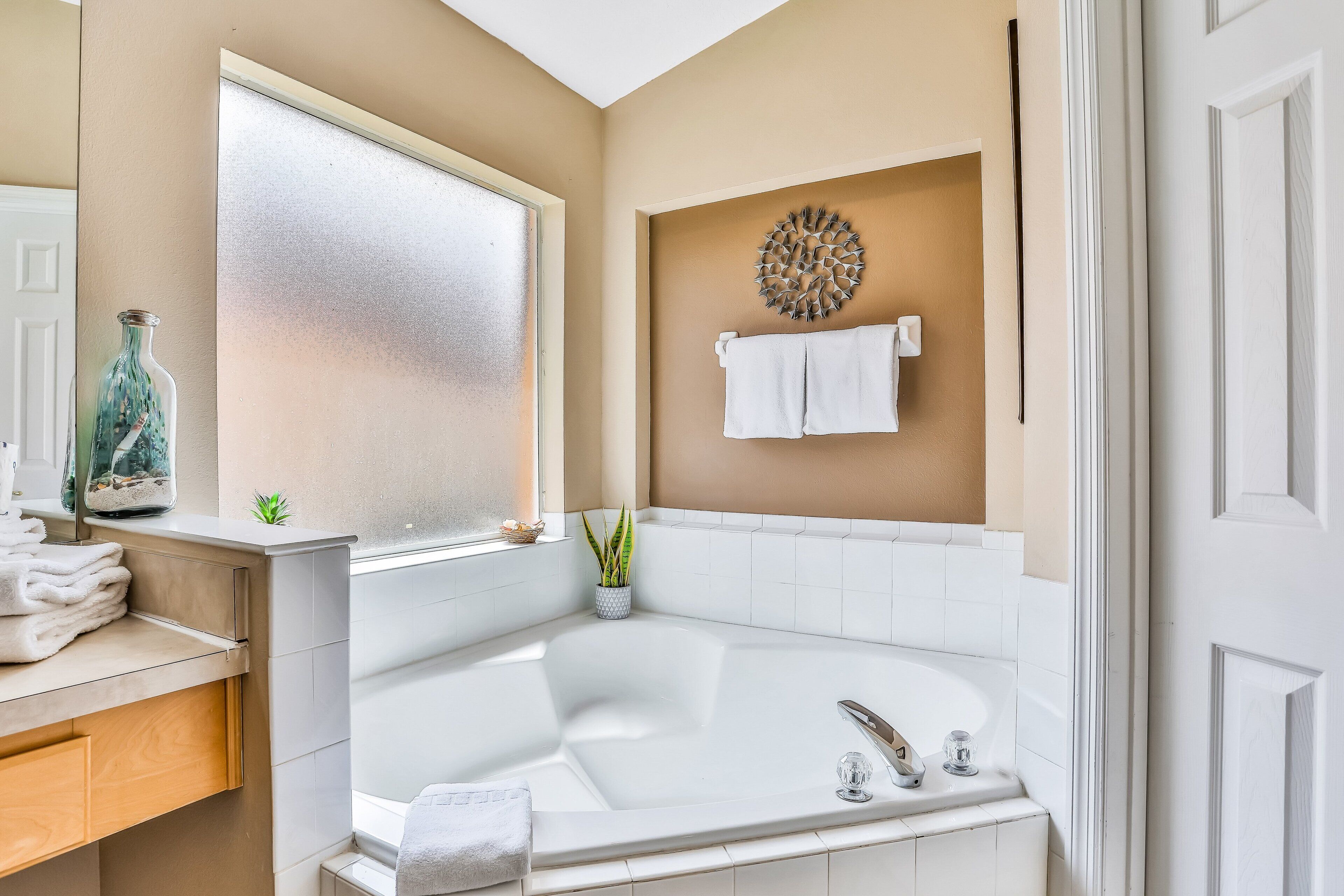 Une salle de bain avec une baignoire, une fenêtre, un porte-serviettes et un élément décoratif mural.
