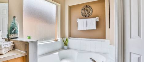 Une salle de bain avec une baignoire, une fenêtre, un porte-serviettes et un élément décoratif mural.