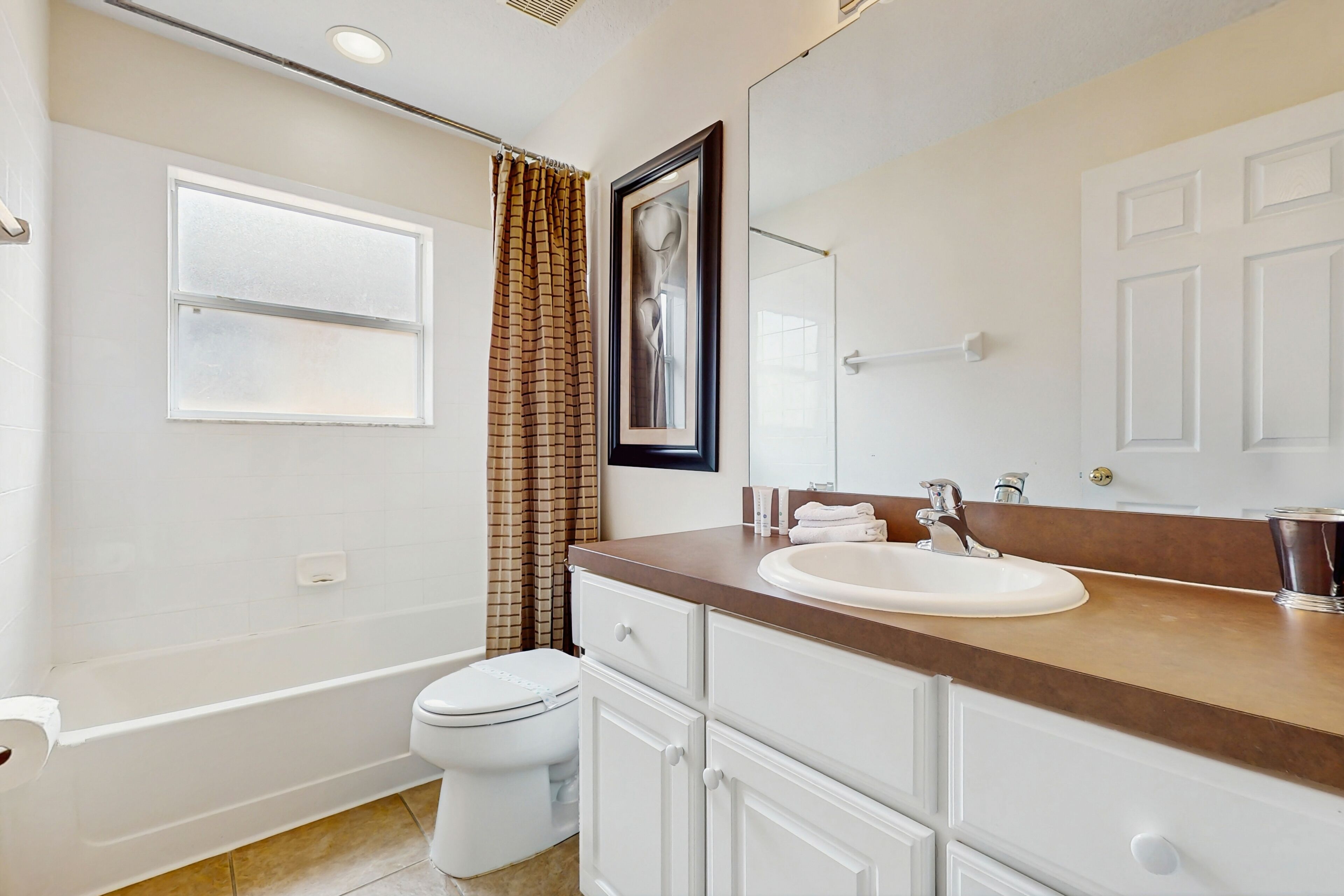 Une salle de bain avec des toilettes blanches, une baignoire, un lavabo avec un miroir et un rideau de douche.