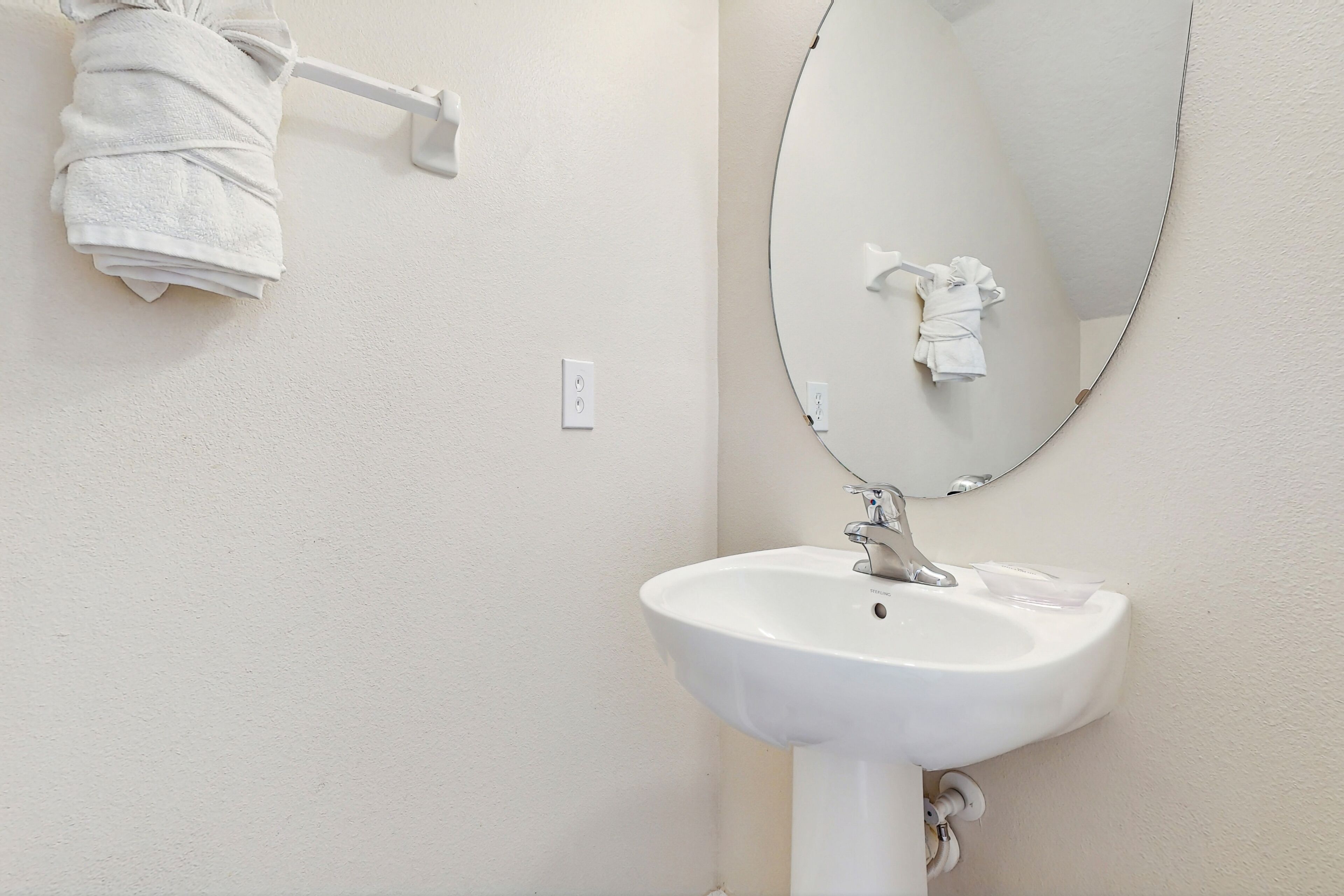 A bathroom with a white sink, a mirror, and a towel rack.