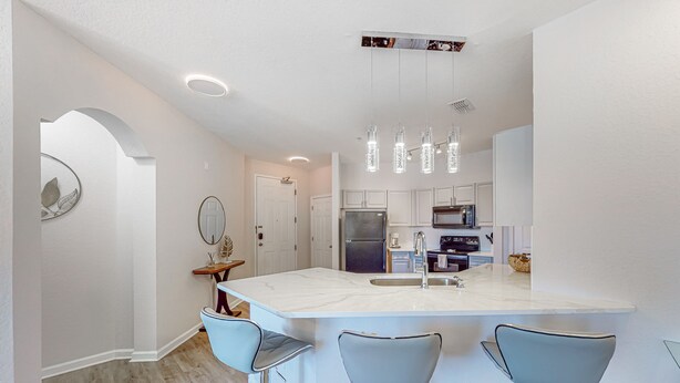 Una cocina moderna con una isla grande, taburetes de bar e iluminación colgante.