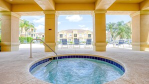 Zona de piscina con jacuzzi, sillas de descanso y vistas a un edificio con palmeras.
