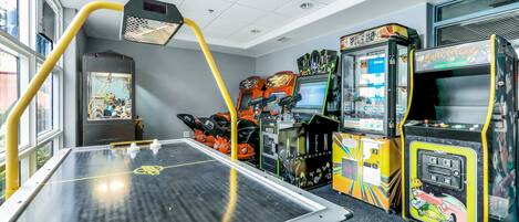 A room with a foosball table, arcade games, and a window with natural light.