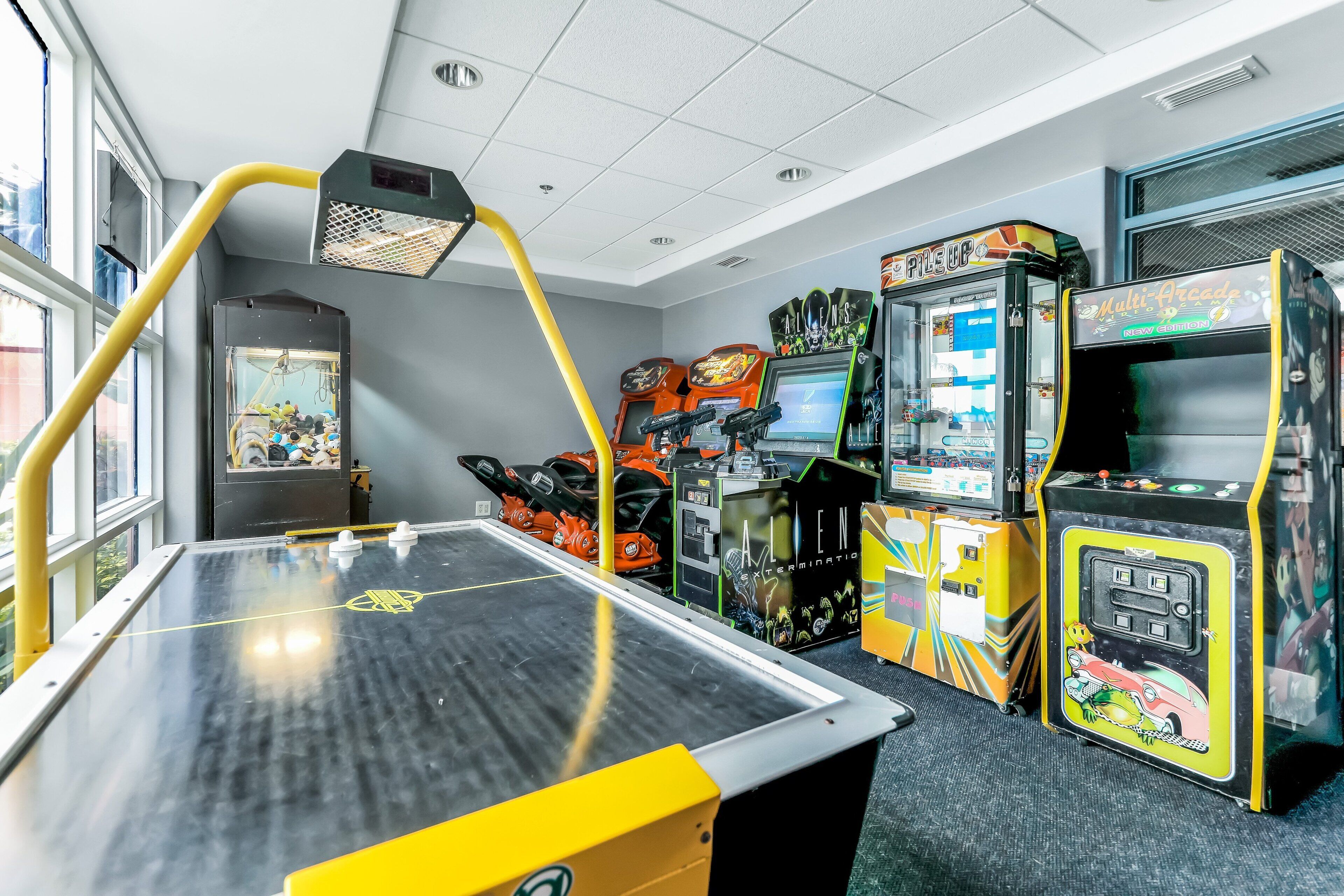 Une pièce avec une table de baby-foot, des jeux d’arcade et une fenêtre.