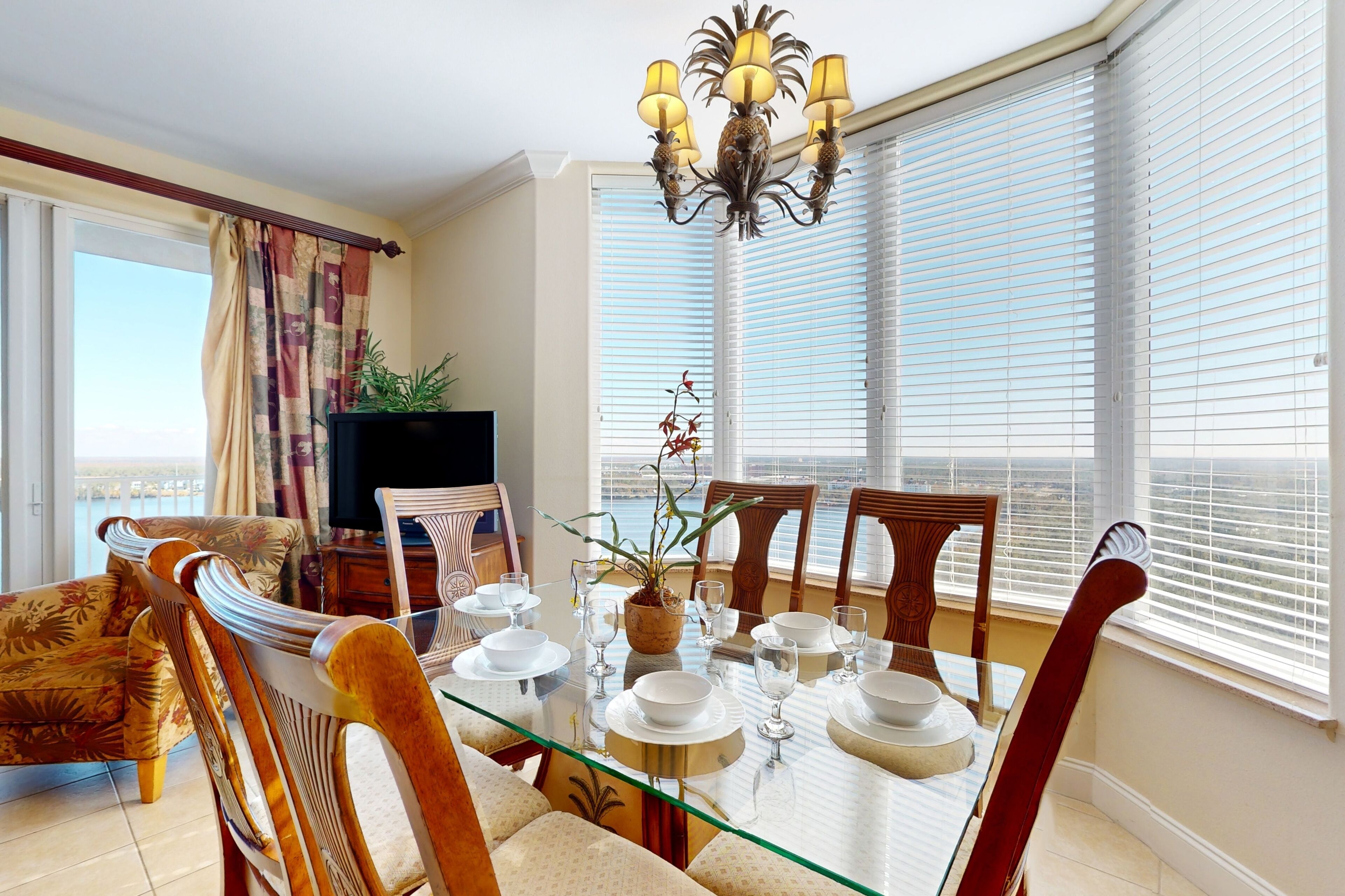 A dining area with a glass table set for four, surrounded by wooden chairs.