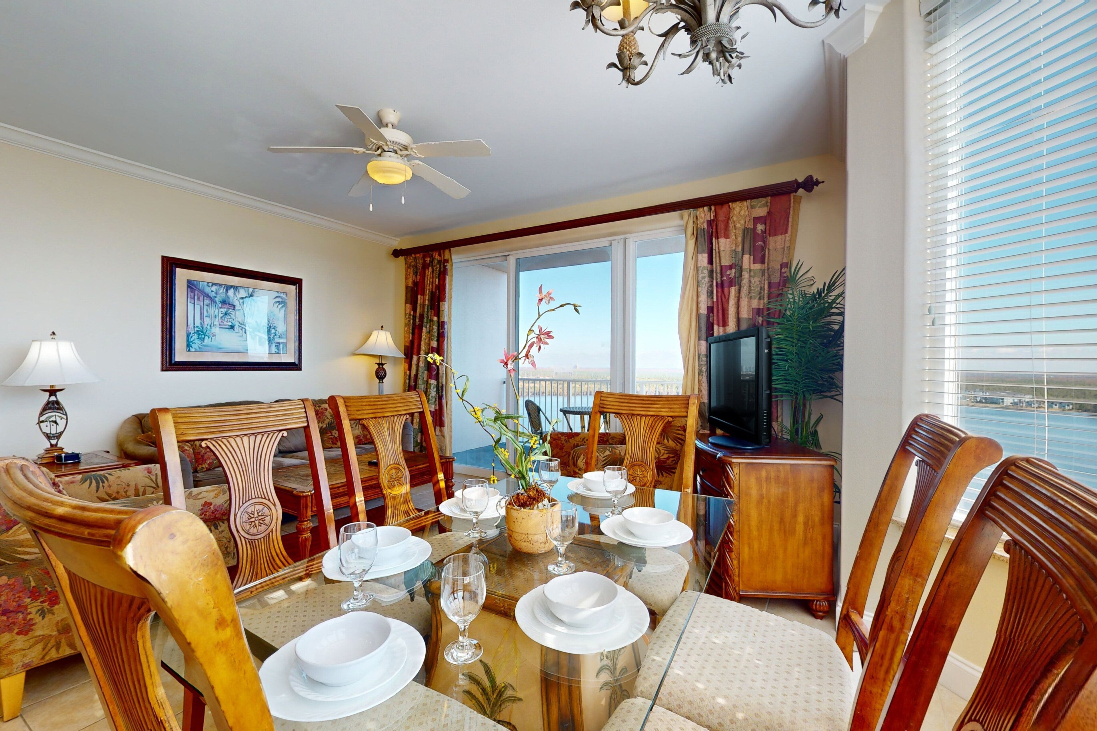A dining area with a glass table, chairs, and a ceiling fan.