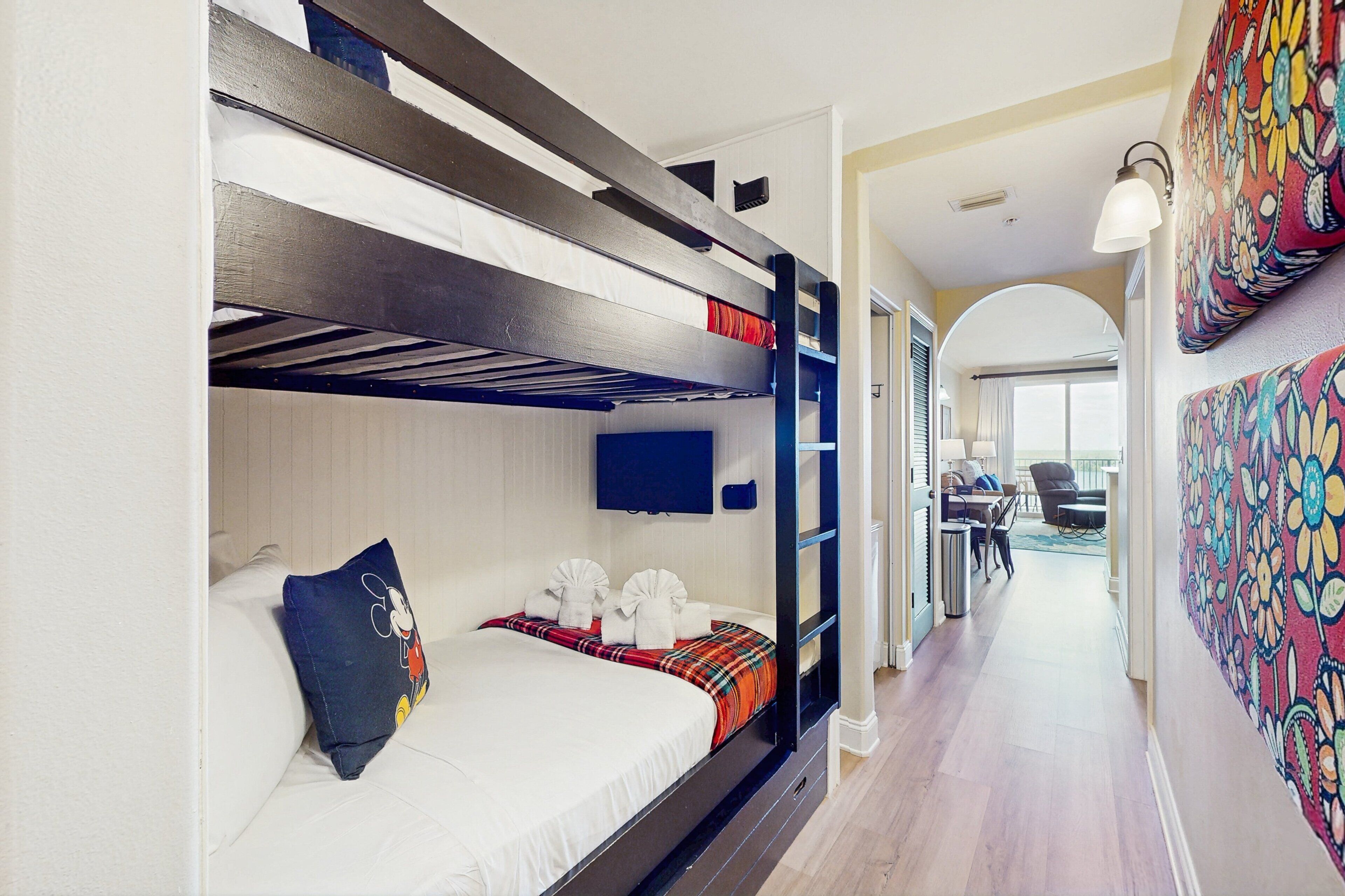 A bunk bed room with a TV, a desk, and a colorful wall.