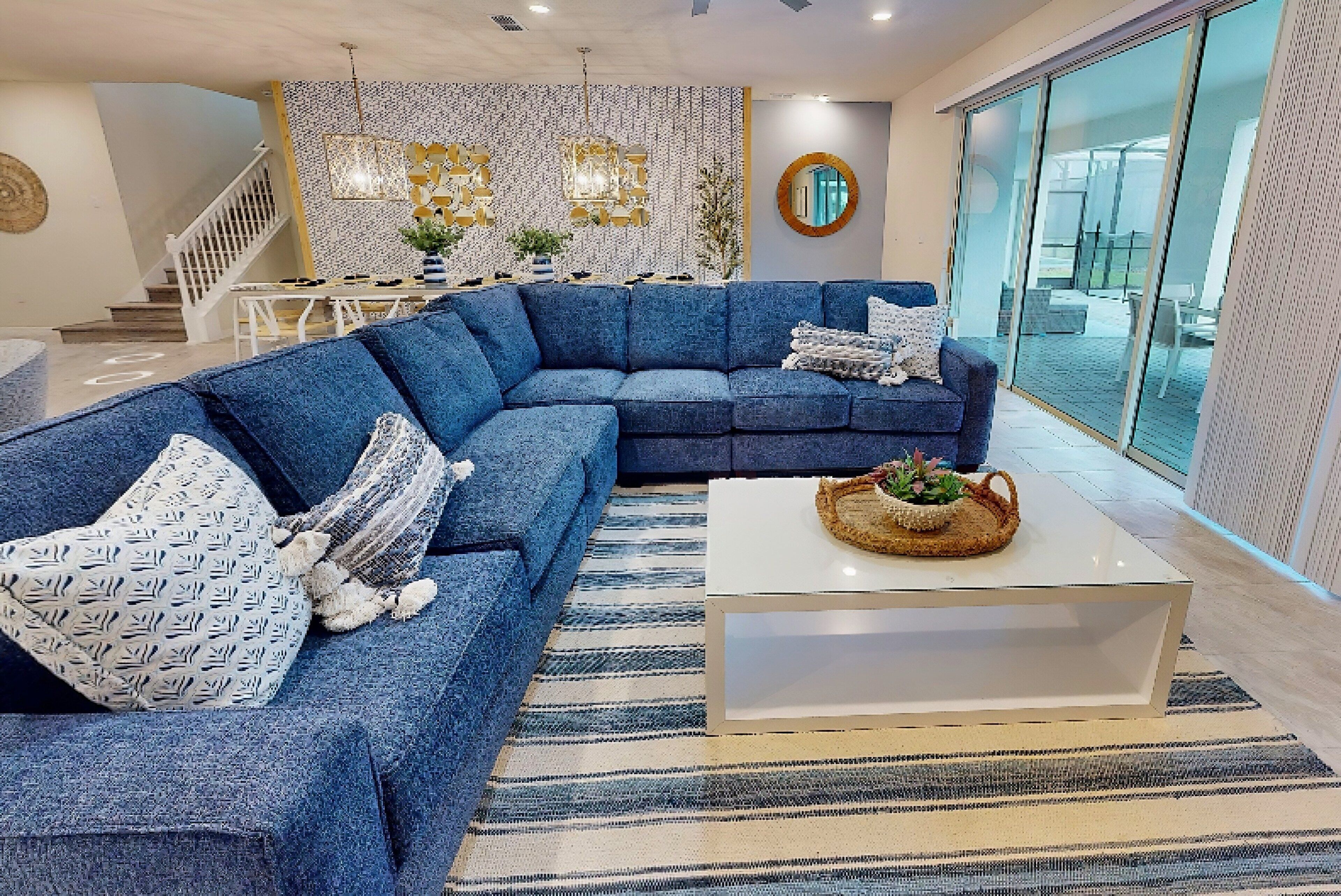 Un salon moderne avec un canapé d’angle, une table basse et un escalier menant à l’étage supérieur.