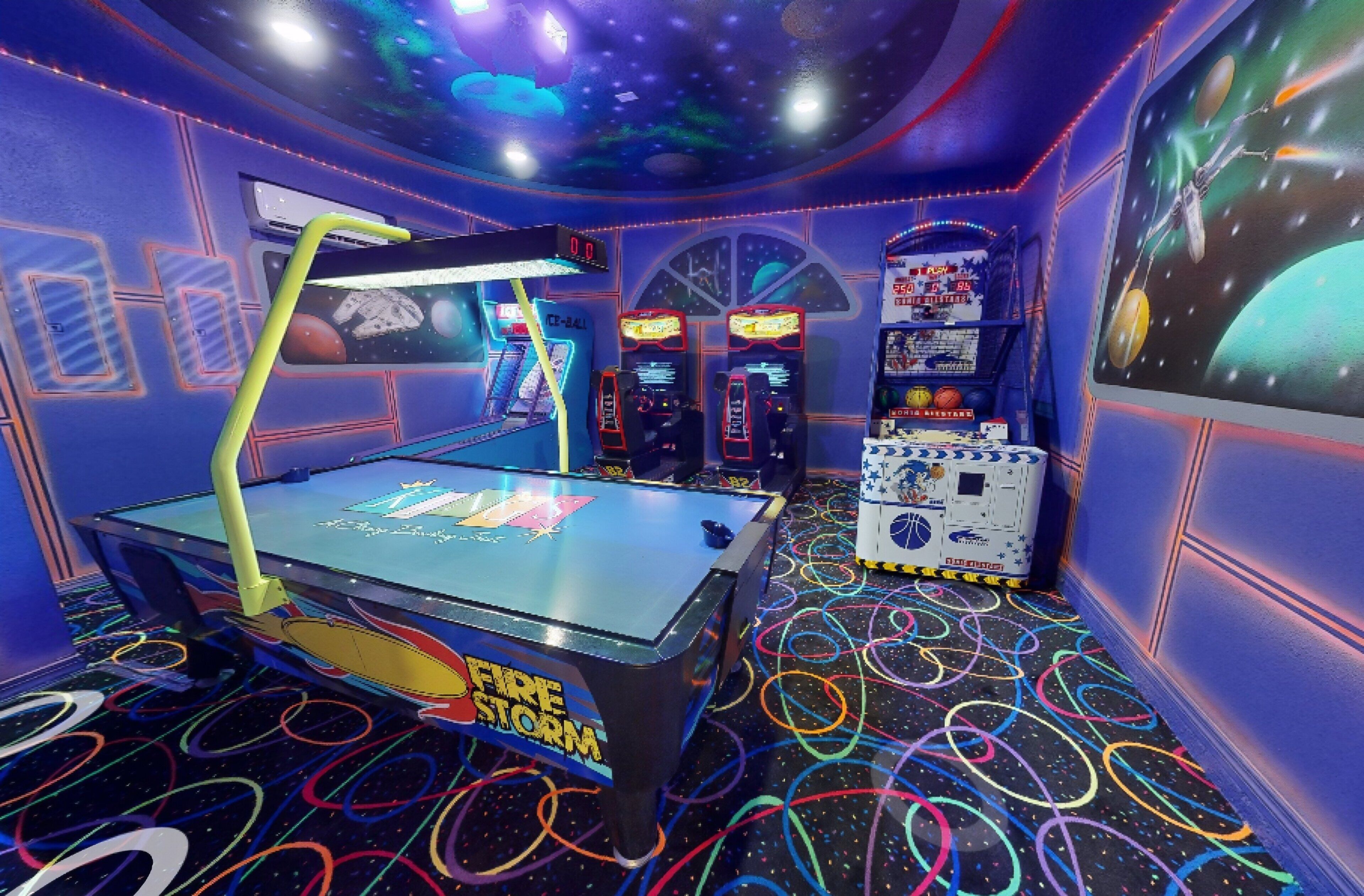 A room with a pool table, arcade games, and a space-themed mural.