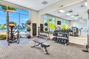 Ein Fitnessraum mit Trainingsgeräten, einer Bank und einem Hantelständer.