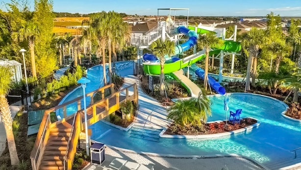 A pool area with a water slide, lounge chairs, and a staircase leading to a pool deck. - Spacious Private Home w/ Private Pool, Resort Style Waterpark & Mini Golf Access (Davenport)