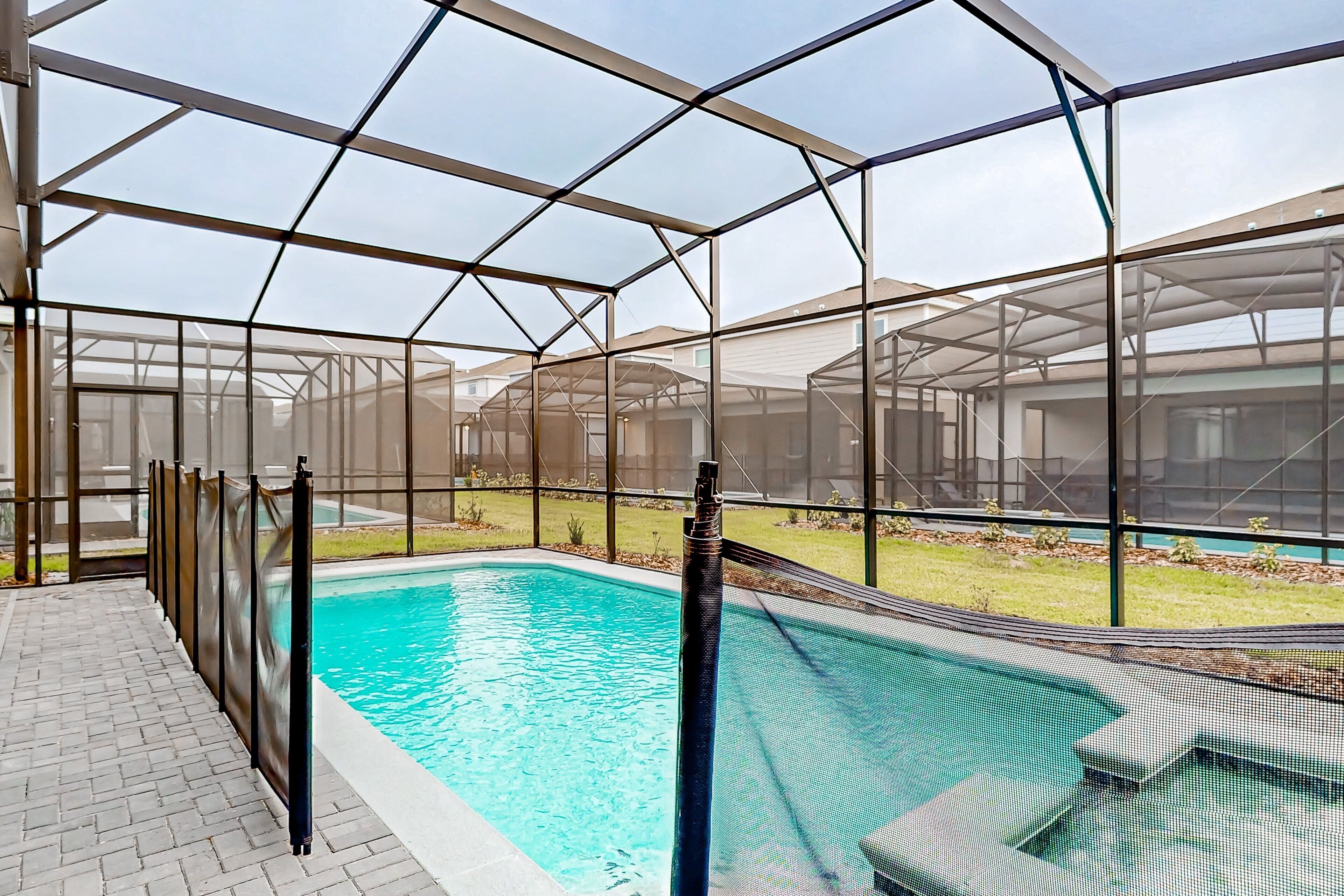 A pool area enclosed by a transparent roof structure, with a clear view of the surrounding buildings.